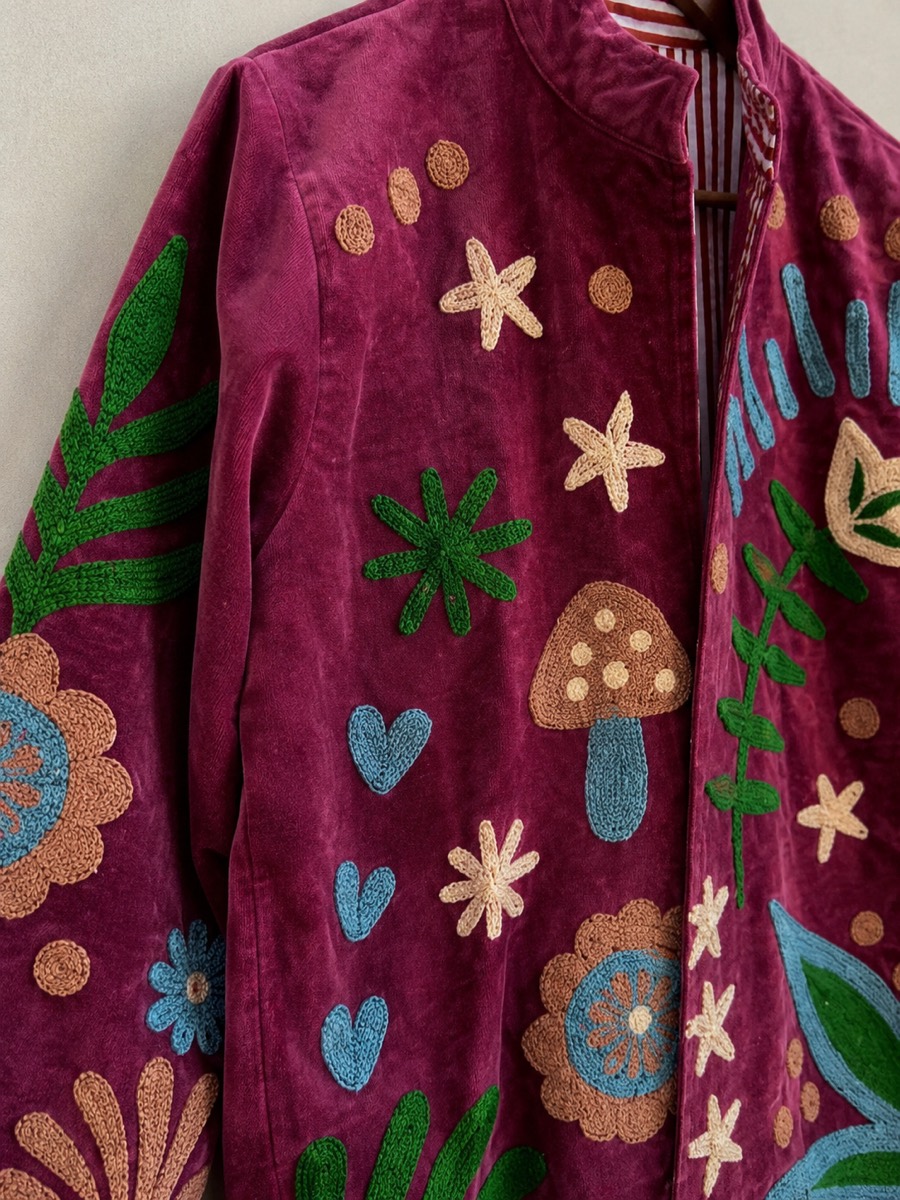 Artisan hand-embroidering gold zardozi botanical motif onto teal velvet